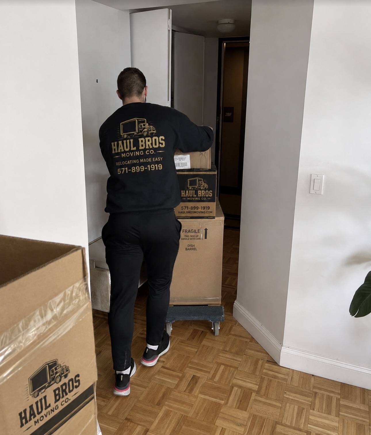 Haul Bros mover transporting boxed belongings through an apartment doorway in Woodbridge