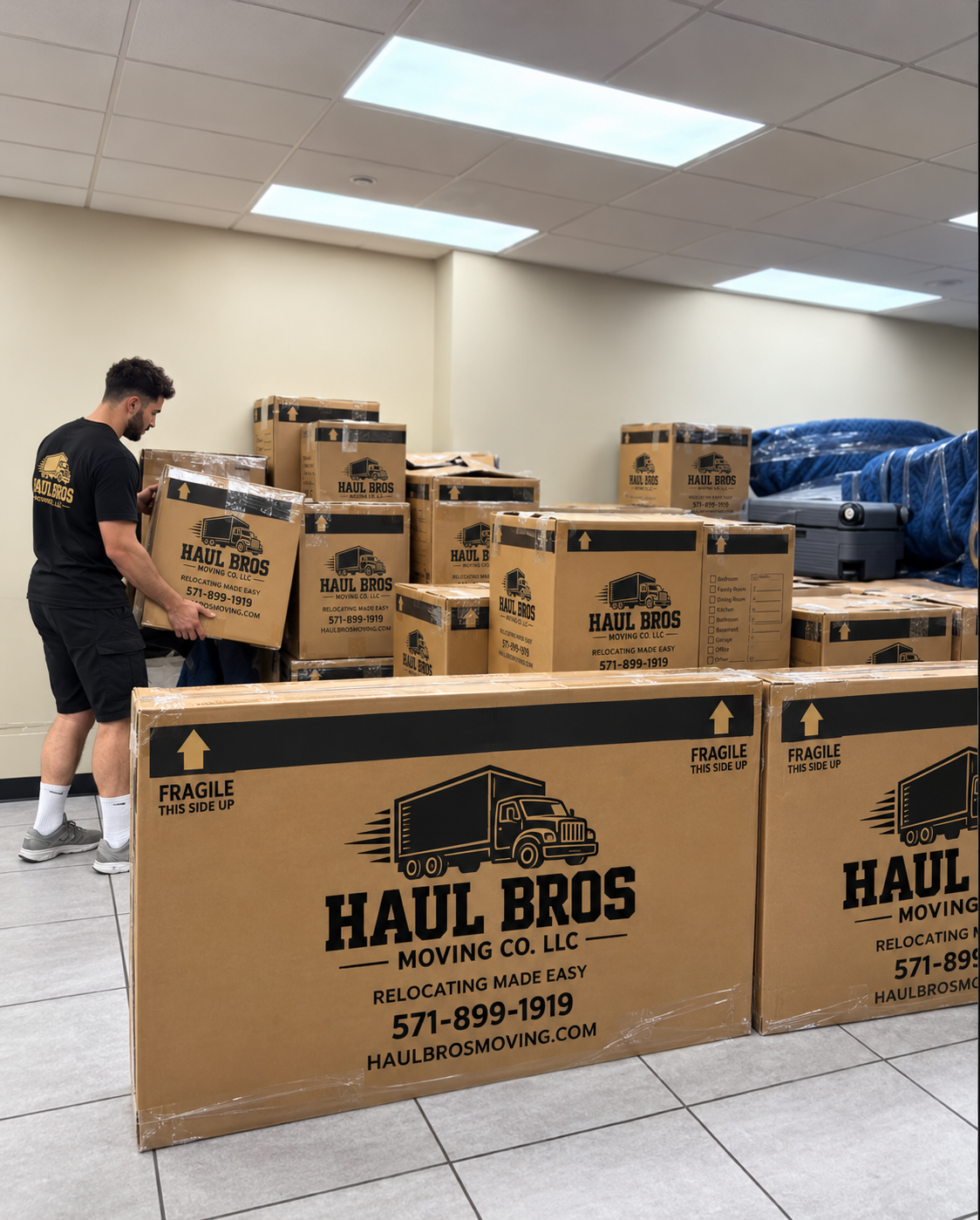 Haul Bros crew member organizing branded moving boxes indoors