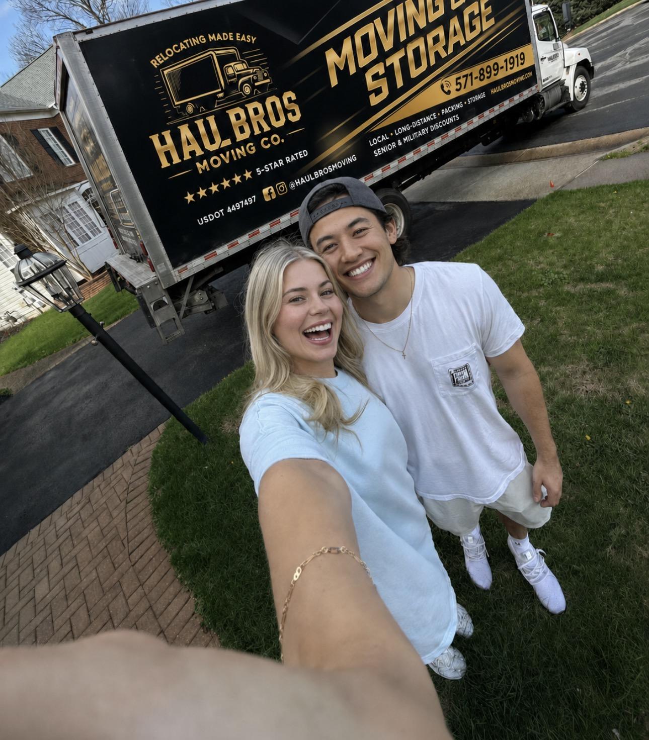 Two people smiling beside a Haul Bros moving truck