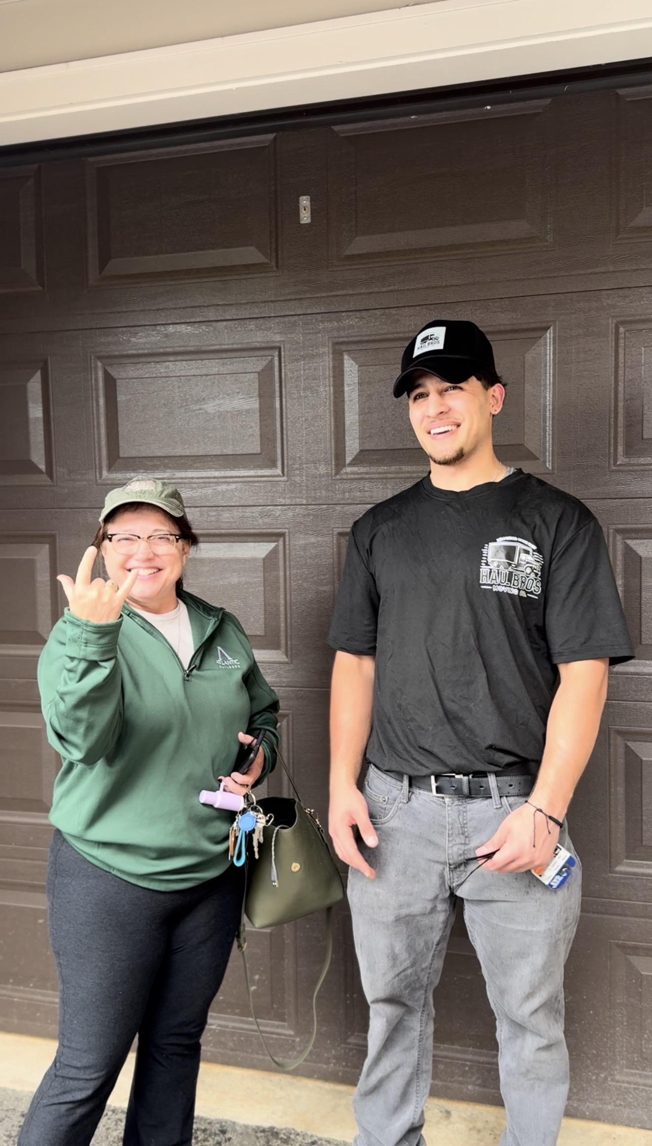 Haul Bros team member and a customer smiling in front of a garage