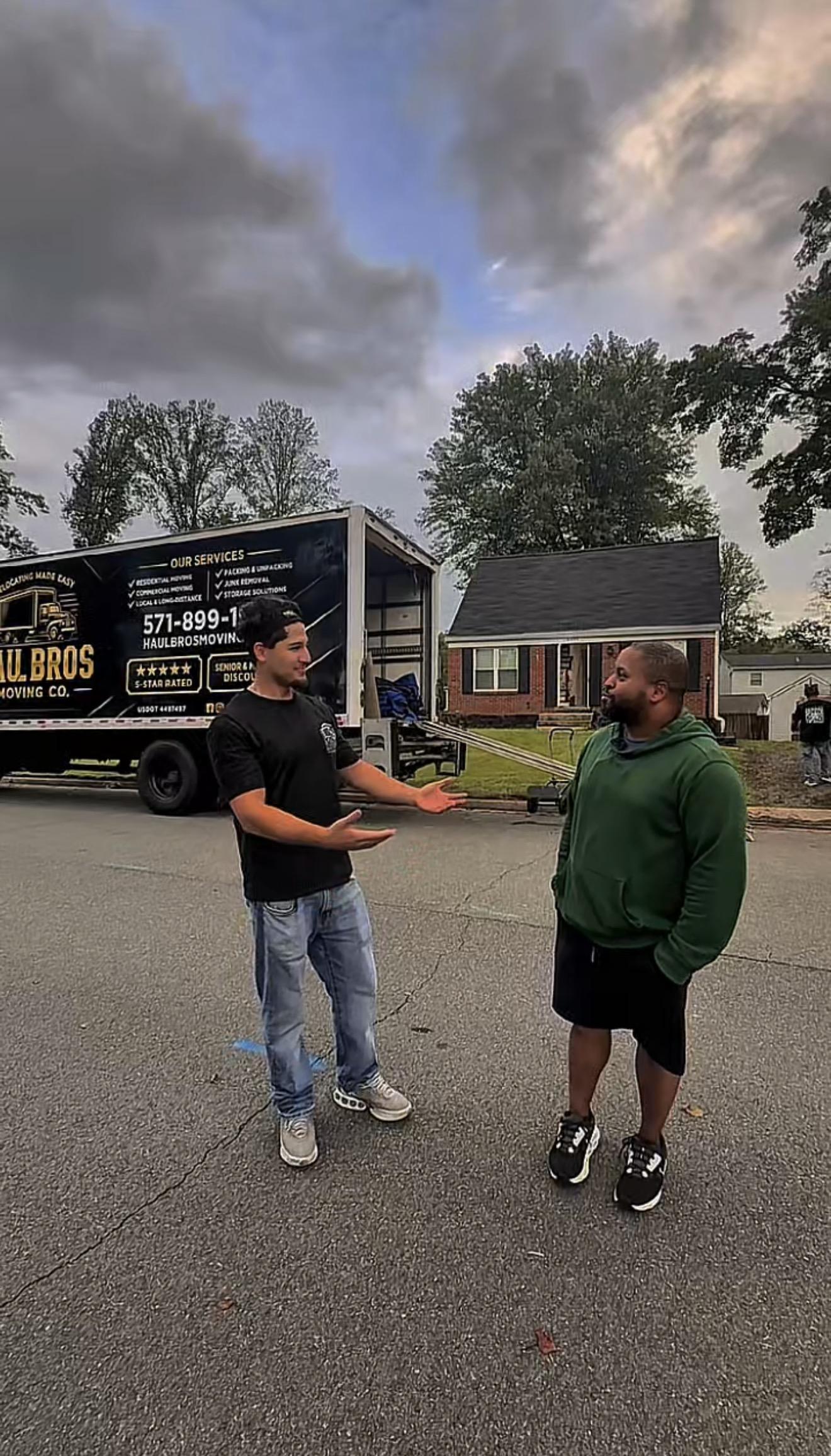 Two people talking beside a Haul Bros moving truck