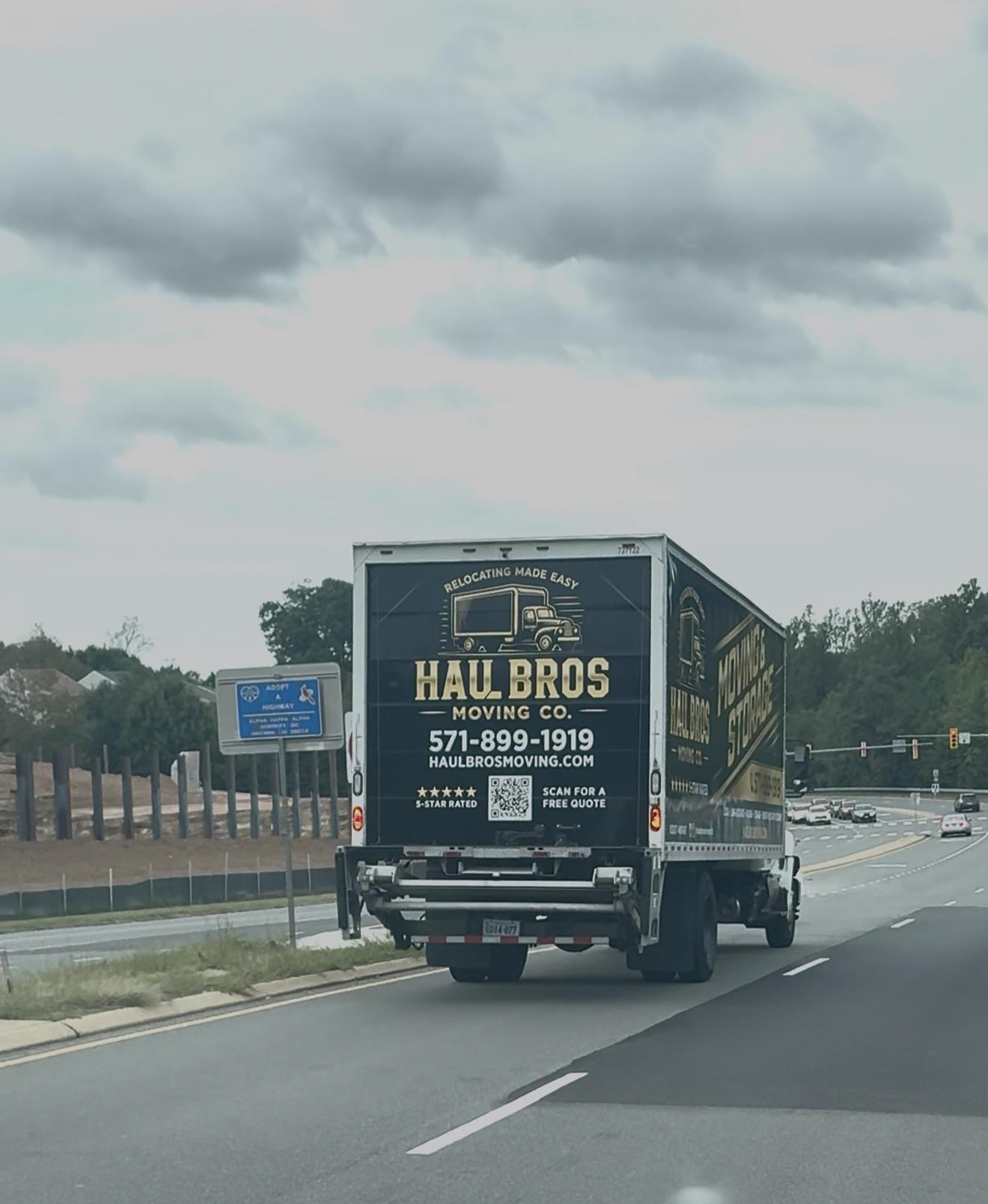 Haul Bros moving truck traveling along a road