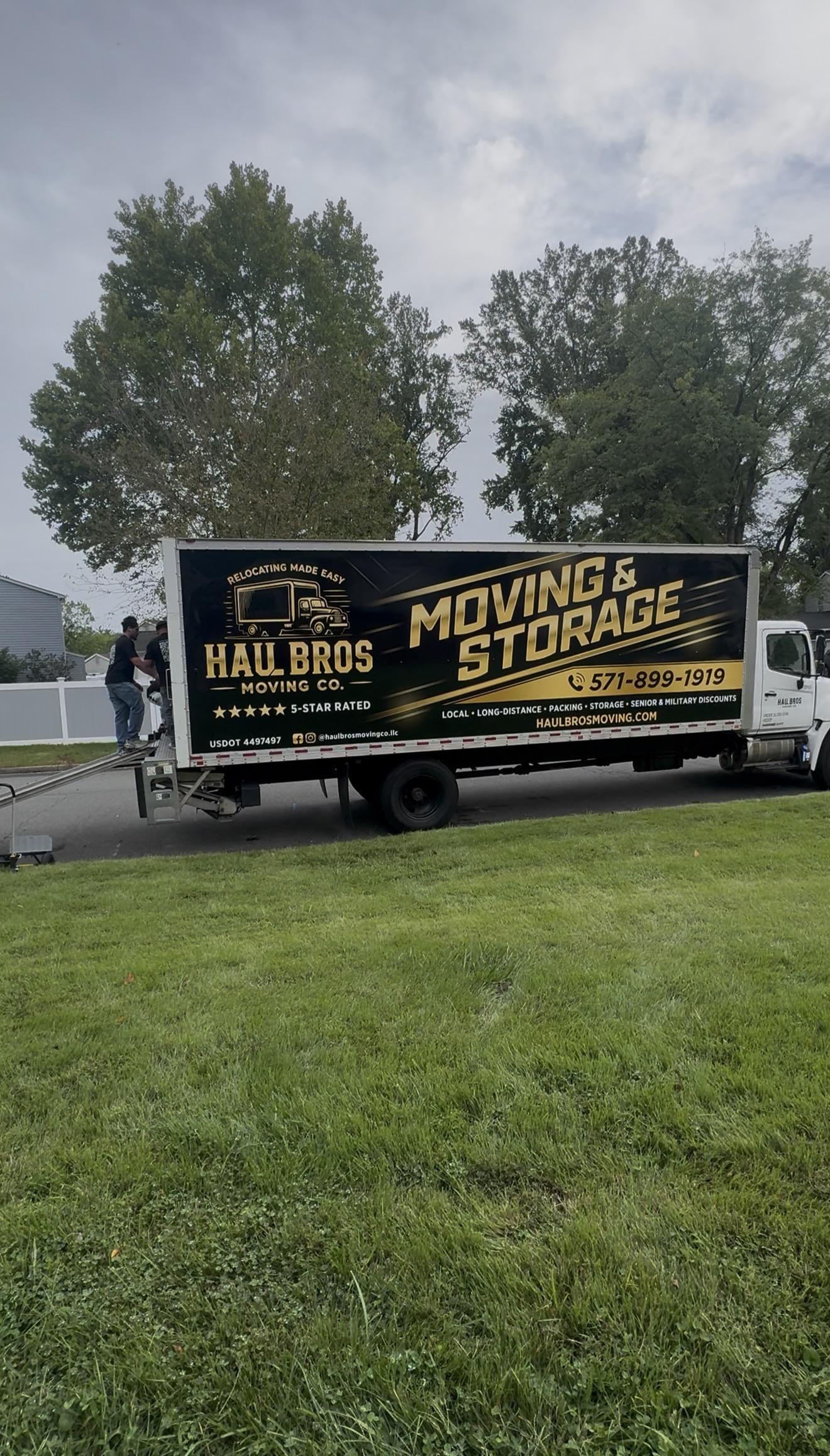 Haul Bros moving and storage truck with crew at the loading ramp on a residential street